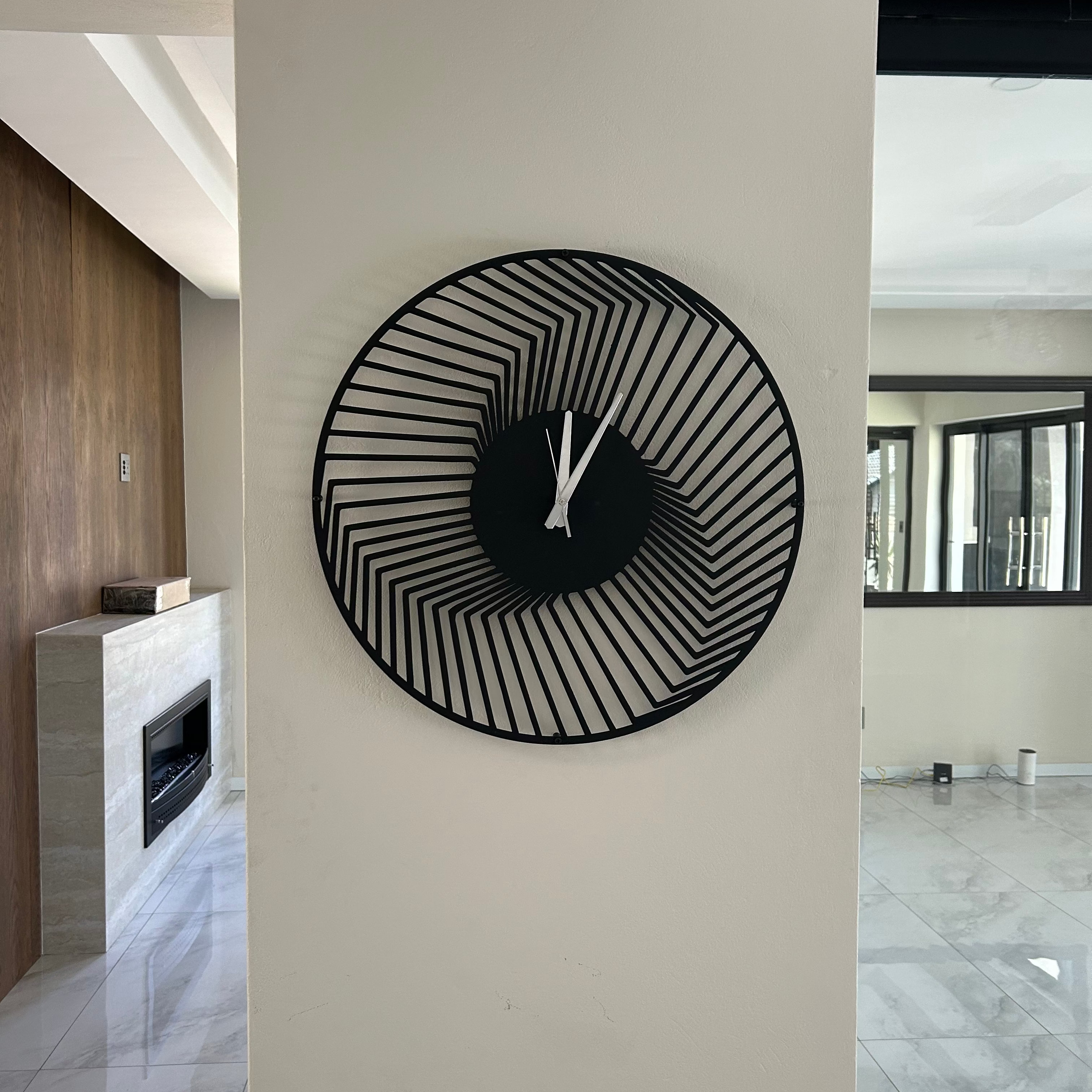 Modern wall clock with black and white design on a white wall in a stylish interior setting.